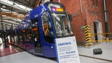 Pesa 2010NW, a przed nią tablica informująca o umowie na modernizację