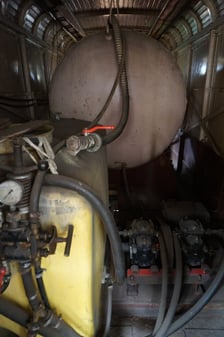 Wnętrze przedziału technicznego tramwaju-opryskiwacza przed remontem ? na pierwszym planie widoczne pompa i plastikowy zbiornik na chemikalia, zaś w tle stalowy zbiornik na wodę
