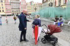 Prezydent Wrocławia Jacek Sutryk rozdaje flagi mieszkańcom i turystom.