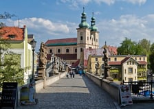 <p>Nie jest tak, że cudze chwalimy, a swojego nie znamy. Po wyjazdach za granicę wracamy na polską, dolnośląską ziemię, a konkretnie na ziemię kłodzką.&nbsp;</p>
<p>Widoczny na zdjęciu gotycki most przerzucony jest nad rzeką Młyn&oacute;wką. Zabytkowa przeprawa łączy Wyspę Piasek ze staromiejską częścią miasta, nad kt&oacute;rym wzosi się Twierdza Kłodzko.&nbsp;</p>
<p>Do Kłodzka z Wrocławia często kursują <strong>pociągi Kolei Dolnośląskich</strong>. Najszybsza podr&oacute;ż trwa godzinę i dwadzieścia kilka minut.&nbsp;</p>
<p>&nbsp;</p>