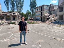 Dima na tle zburzonej przez Rosjan szkoły, do której chodził.