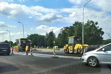 Na ul. Kosmonautów trwają prace budowlane, robotnicy układają masę bitumiczną.
