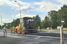 Na ul. Kosmonautów trwają prace budowlane, robotnicy układają masę bitumiczną.