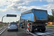 Na ul. Kosmonautów trwają prace budowlane, robotnicy układają masę bitumiczną.