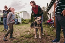 Uśmiechnięta kobieta i chłopiec stojący z psem podczas zajęć z gotowania
