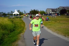 Maratończyk, senior prof. Jan Chmura biegnący ostatnie 20 km w maratonie na Alasce. W tle widać innych zawodników, kibiców i domy