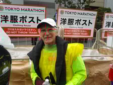 Mężczyzna, senior, prof. Jan Chmura, w stroju biegacza, za nim napis TOKYO MARATHON po angielsku i po japońsku