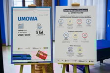 <p>Z lewej: plansza z informacją o podpisanej umowie. Urbancard w pociągach 2026-2030. Umowa na 5 lat za ok. 242 mln złotych. Z prawej: plansza z informacją o rodzajach honorowanych bilet&oacute;w, uprawnieniach do bezpłatnych przejazd&oacute;w oraz przystankach kolejowych objętych umową.</p>