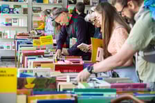 <p>Czytelnicy przeglądający książki i inne zbiory wystawione na sprzedaż w Dolnośląskiej Bibliotece Publicznej w rynku</p>