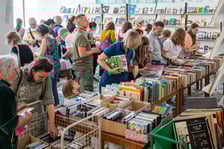 <p>Czytelnicy przeglądający książki i inne zbiory wystawione na sprzedaż w Dolnośląskiej Bibliotece Publicznej w rynku</p>