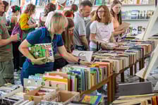 <p>Czytelnicy przeglądający książki i inne zbiory wystawione na sprzedaż w Dolnośląskiej Bibliotece Publicznej w rynku</p>