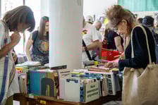 <p>Czytelnicy przeglądający książki i inne zbiory wystawione na sprzedaż w Dolnośląskiej Bibliotece Publicznej w rynku</p>