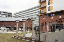 <p>Ceglane pozostałości po koszarach i nowy blok w lutym 2024</p>