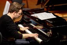 <p>Piotr Alexewicz podczas pr&oacute;by w sali czerwonej Narodowego Forum Muzyki</p>