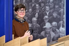 <p>Agata Gabiś, jedna z kuratorek wystawy "Niedziela w Hutmenie" w Muzeum Architektury we Wrocławiu, w tle zdjęcie pracownik&oacute;w zakładu ze zbior&oacute;w Ossolineum wykonane przez S. Kokuroicza w 1975 roku</p>