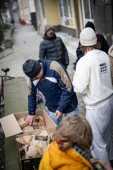 <p>mężczyzna zaglądający do kartonu z produktami spożywczymi</p>