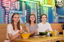 <p>Trzy młode, uśmiechnięta klientki Vegan AF Ramen przy stoliku, na kt&oacute;rym stoją miski z ramenem</p>