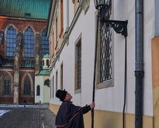 Na zdjęciu widać mężczyznę, który zapala latarnię na Ostrowie Tumskim we Wrocławiu