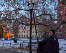 Na zdjęciu widać mężczyznę, który zapala latarnię na Ostrowie Tumskim we Wrocławiu