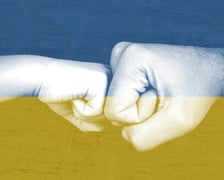 "Ukraina" była najszybciej zyskującym na popularności hasłem w Polsce wg zestawienia Google Trends 2022. Na zdjęciu dwie dłonie na tle flagi Ukrainy