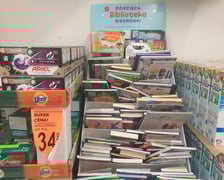 Tekturowy regał wystawienniczy (ustawiony między proszkami do prania), na którym wyeksponowano książki