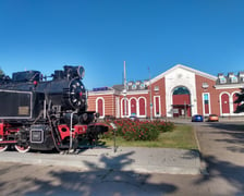 <p>Zabytkowa lokomotywa i w tle dworzec kolejowy w Kramatorsku</p>
