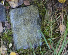 fragment płyty nagrobnej wmurowanej w ocembrowanie stawu