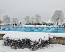 Basen na świeżym powietrzu w Malveno we Włoszech, 3-7.02.2026,  przed nim fragment żywopłotu pod śniegiem, w tle ośnieżone drzewa