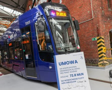 Pesa 2010NW, a przed nią tablica informująca o umowie na modernizację