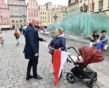 Prezydent Wrocławia Jacek Sutryk rozdaje flagi mieszkańcom i turystom.