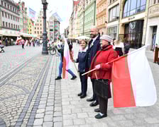 Prezydent Wrocławia Jacek Sutryk rozdaje flagi mieszkańcom i turystom.