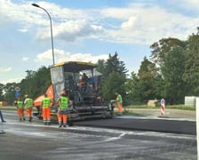 Na ul. Kosmonautów trwają prace budowlane, robotnicy układają masę bitumiczną.