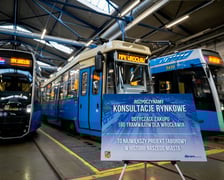 Konferencja MPK Wrocław na zajezdni Borek: tablica z informacją o konsultacjach rynkowych i trzy tramwaje - Konstal 105 i dwie Pesy 146N