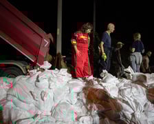 Kobiety i mężczyźni układają worki z piaskiem na Marszowicach w nocy z 17 na 18 września 2024 roku