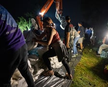 Kobiety i mężczyźni układają worki z piaskiem na Marszowicach w nocy z 17 na 18 września 2024 roku