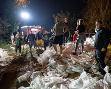 Kobiety i mężczyźni układają worki z piaskiem na Marszowicach w nocy z 17 na 18 września 2024 roku