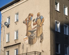 <p>Mozaika na elewacji domu nr 11 przy ul. Ustronie pokazuje dw&oacute;ch kowali przy pracy</p>