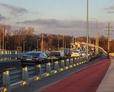 Aleja Wielkiej Wyspy w blasku zachodzącego słońca. Droga rowerowa i oddzielona od niej ulica z samochodami