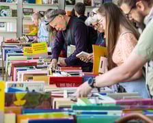 <p>Czytelnicy przeglądający książki i inne zbiory wystawione na sprzedaż w Dolnośląskiej Bibliotece Publicznej w rynku</p>