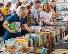 <p>Czytelnicy przeglądający książki i inne zbiory wystawione na sprzedaż w Dolnośląskiej Bibliotece Publicznej w rynku</p>