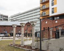 <p>Ceglane pozostałości po koszarach i nowy blok w lutym 2024</p>