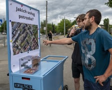 Konsultacje w sprawie terenu TBS-u przy ul. Głubczyckiej we Wrocławiu. Na zdjęciu widać dwóch mężczyzn analizujących plan inwestycji zawieszony na wózku konsultacyjnym.