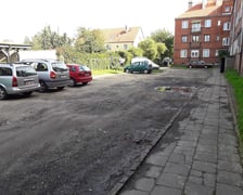 Podwórko przy Hallera przed rewitalizacją - widok na nieutwardzony parking z dziurami i kałużami