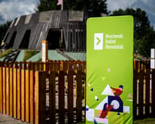 <p>Zielony baner z logotypem Wrocławskiego Budżetu Obywatelskiego (WBO). W tle plac zabaw "Średniowieczny Wrocław" w parku Tysiąclecia - zrealziowany dzięki głosom oddanym w WBO.</p>