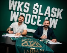 Karol Linetty (z lewej) i Remigiusz Jezierski, prezes Śląska Wrocław (z prawej) siedzą przy stole na którym leży koszulka klubowa, w tle na ścianie biały napis "WKS Śląsk Wrocław"..