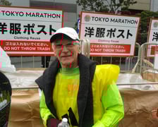 Mężczyzna, senior, prof. Jan Chmura, w stroju biegacza, za nim napis TOKYO MARATHON po angielsku i po japońsku
