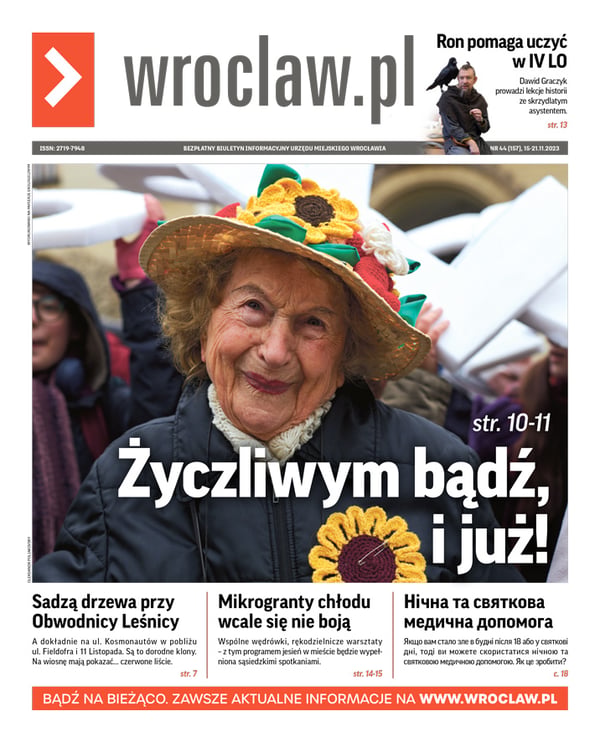 Zdjecie okładki biuletynu - Na zdjęciu 98-letnia pani Iza w kapeluszu z żółtymi kwiatami słonecznika zrobionymi na szydełku; żółty słonecznik ma też przypięty agrafką do ciemnego płaszcza