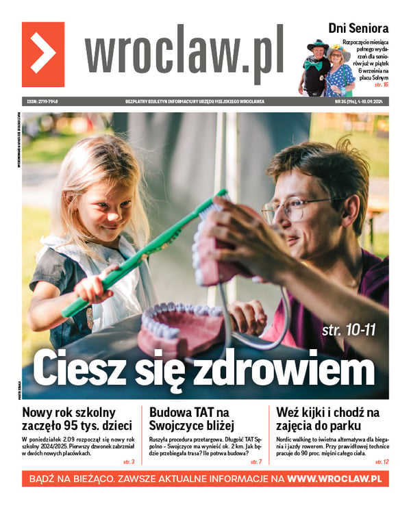 Zdjecie okładki biuletynu - Dziewczynka wielką szczoteczką do zębów myje górne zęby w ogromnym modelu sztucznej szczęki, którą trzyma jej tata podczas 14. Dni Promocji Zdrowia we Wrocławiu