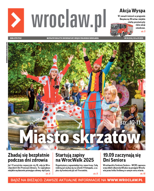 Zdjecie okładki biuletynu - Kobieta i mężczyzna na szczudłach przebrani za krasnale: ona w czerwono-białym stroju i czapce, mężczyzna  w czerwono-niebiesko-żółtym z podniesionymi do góry rękami w parku Staromiejskim podczas Festiwalu Krasnoludków