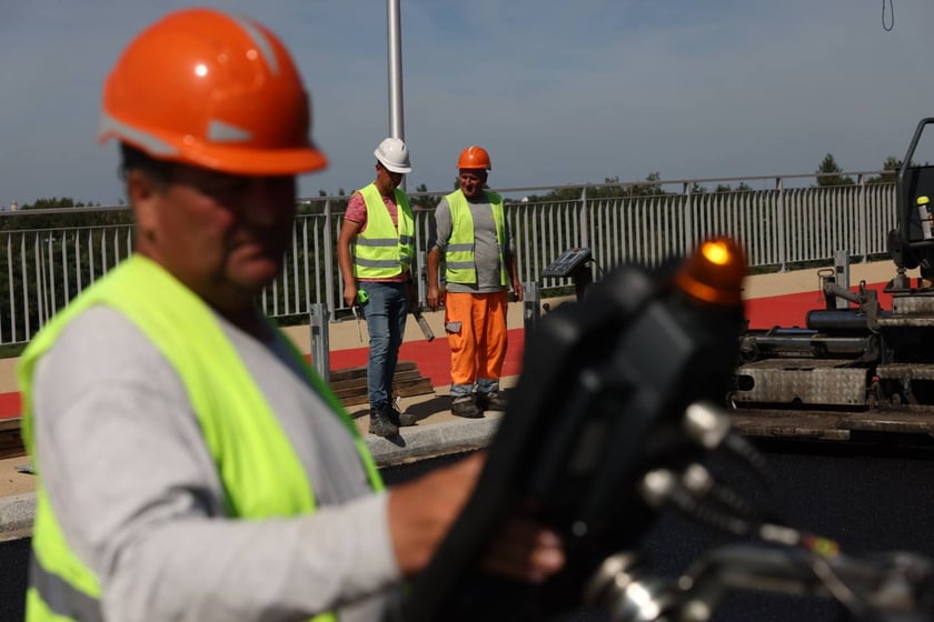 Robotnicy pracujący na wiadukcie, układają ostatnią warstwę nawierzchni
